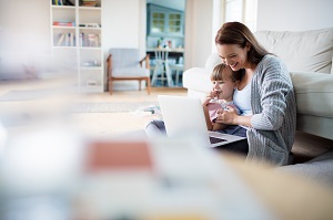 mother with daughter on lap on laptop