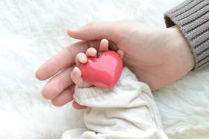 mom holding baby's hand, baby holding heart